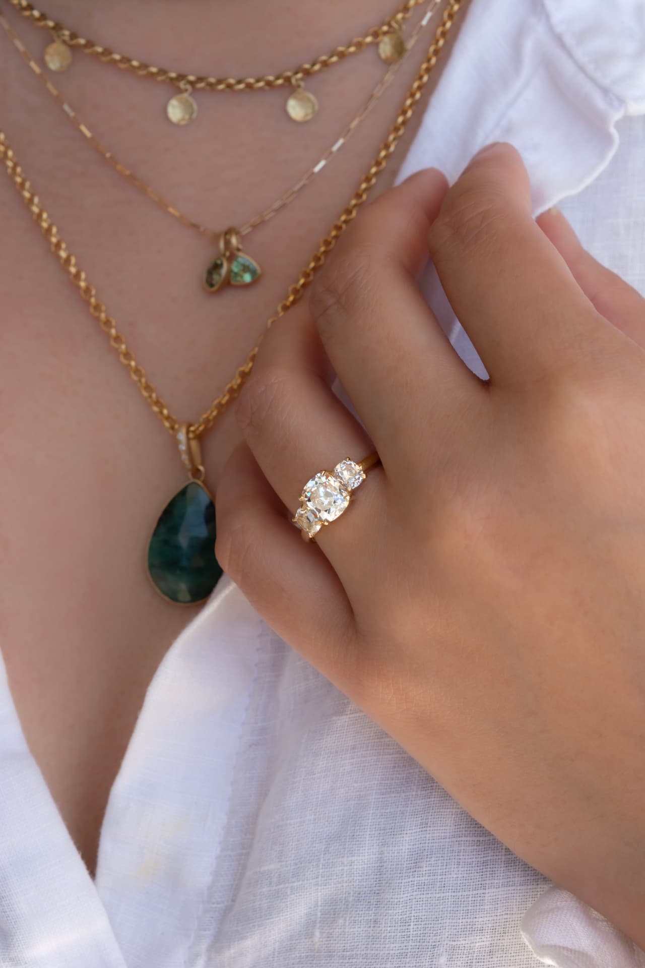 Diamond ring styled with layered gold and gemstone necklaces